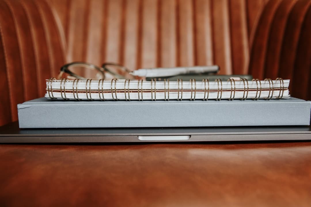 Leather ledger and paperwork on a wooden desk in natural light.